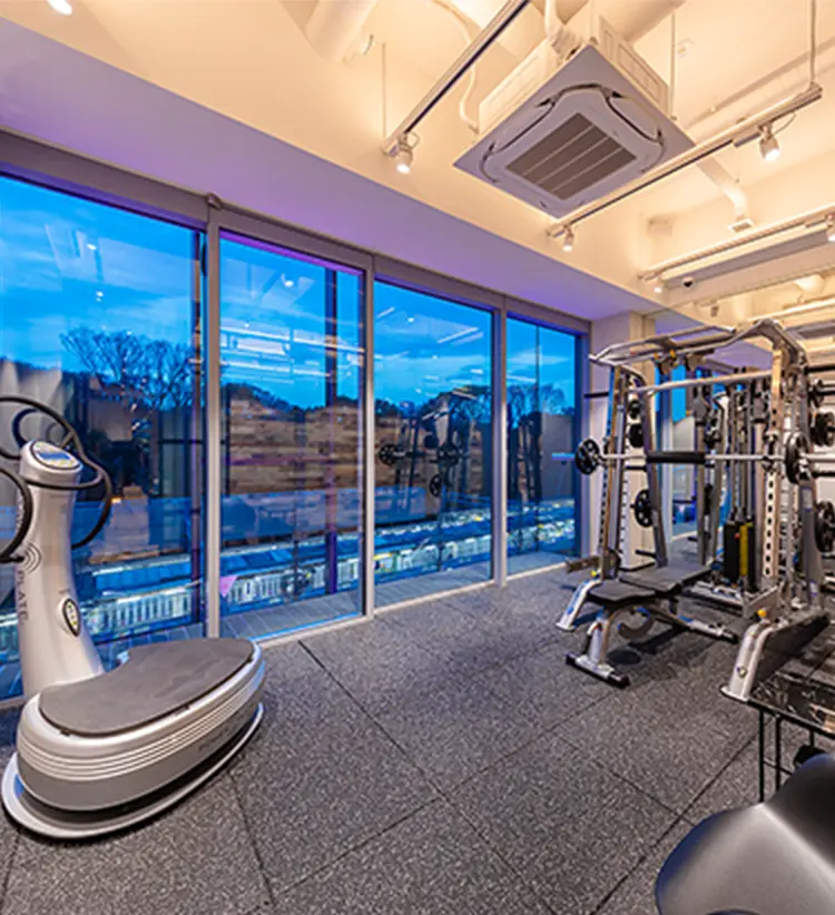 大型ガラス窓から夜景が見えるトレーニングジムの内観